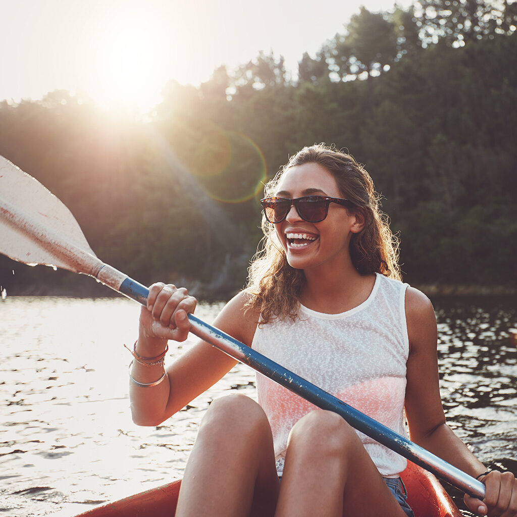 smiling young woman kayaking on a lake